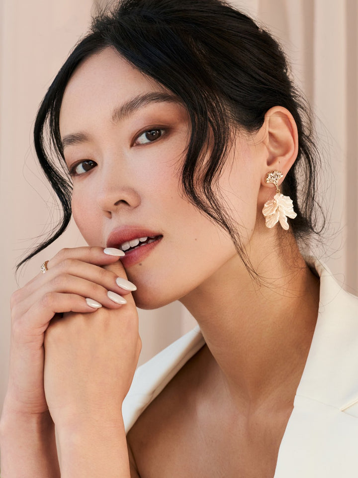Woman wearing floral earrings with a neutral background
