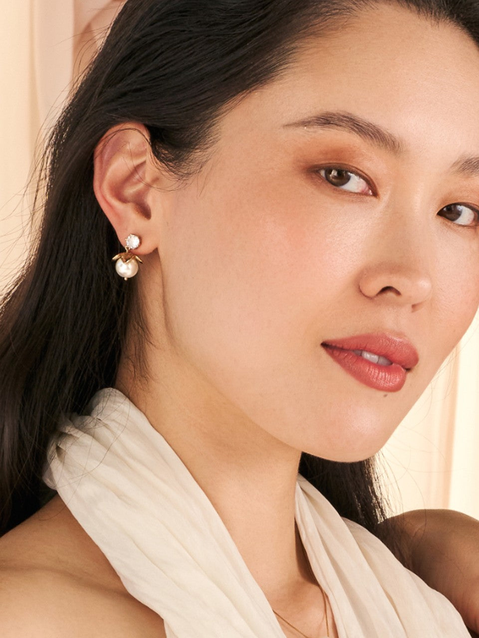 Close-up of a woman wearing drop earrings with a soft background